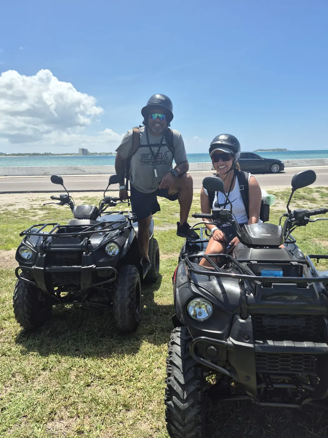 Two ATV riders on the grass by the sea