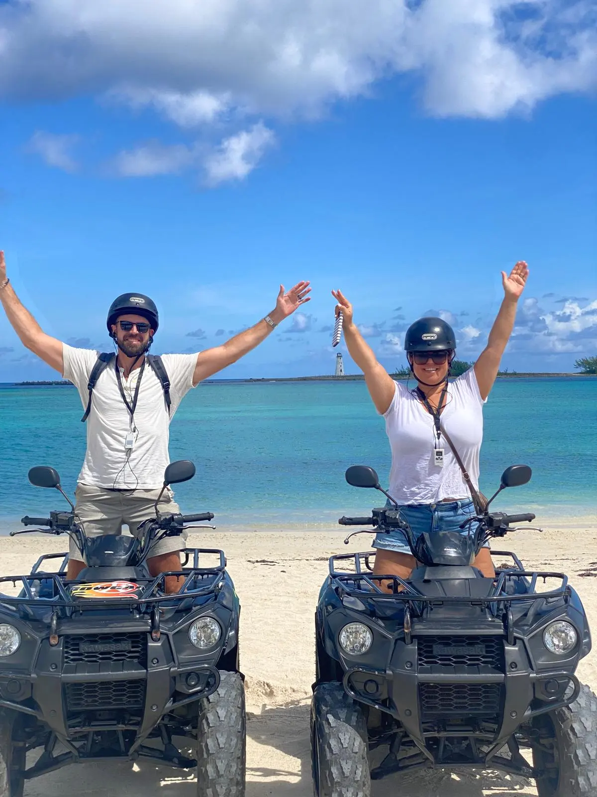 Two riders celebrating on their ATVs at the beach
