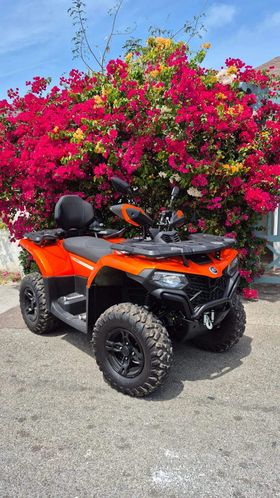 An orange Bowcar ATV under pink bougainvillea