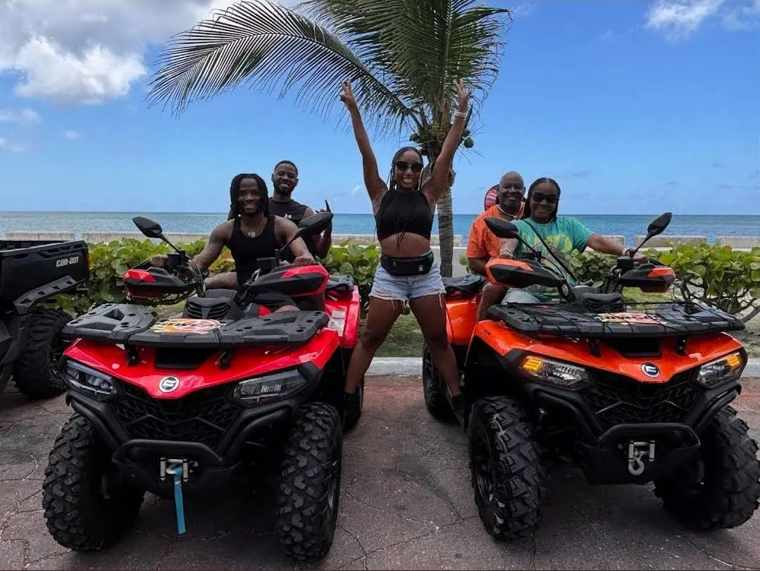 Two guests on ATVs raising their arms by the sea in Nassau