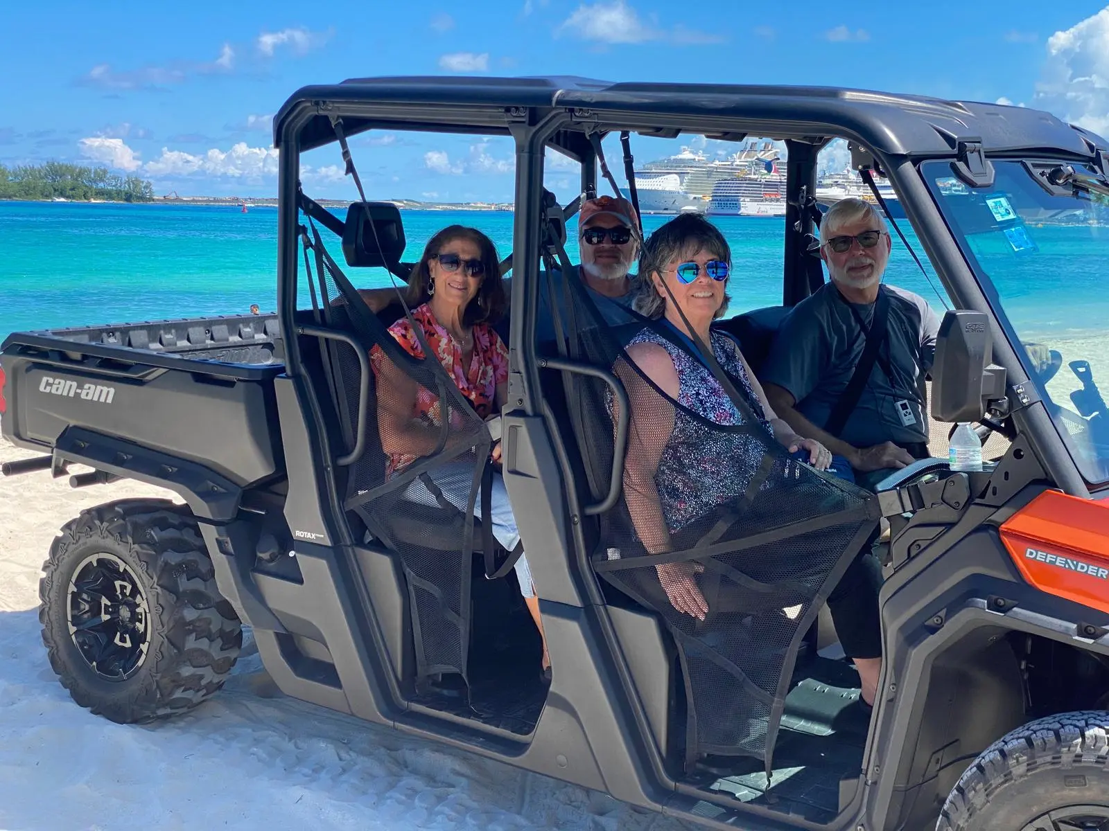 A family in a black Can-Am buggy beside turquoise water