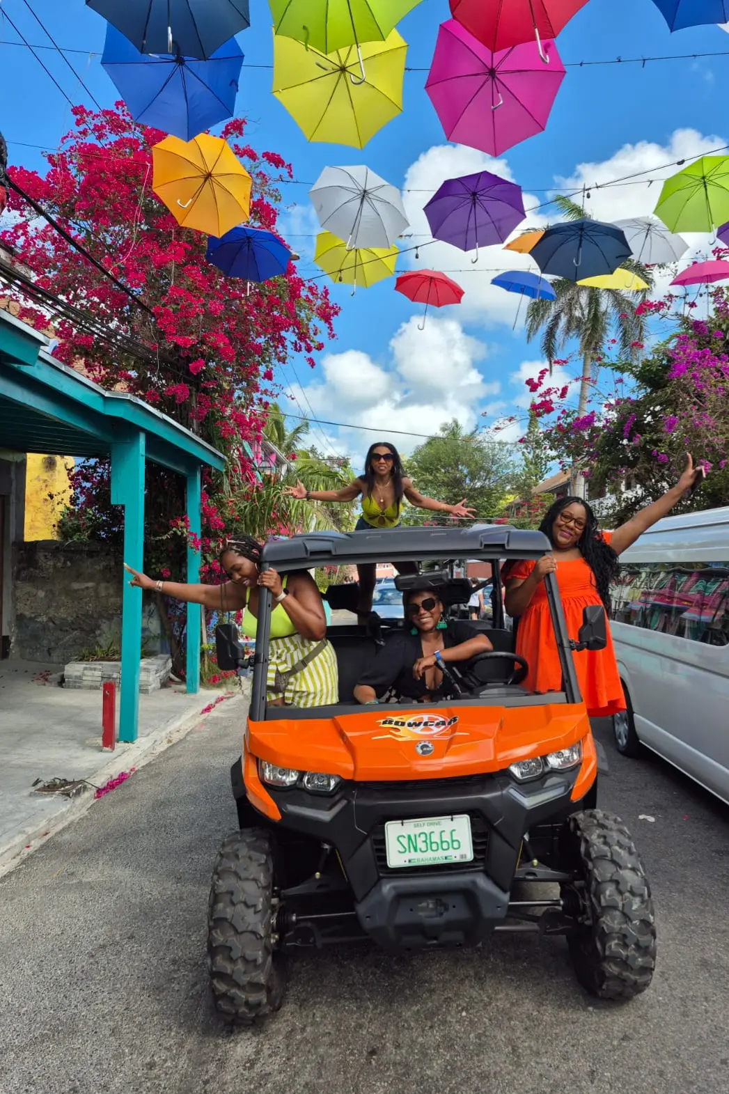 An orange buggy under a street of colourful umbrellas