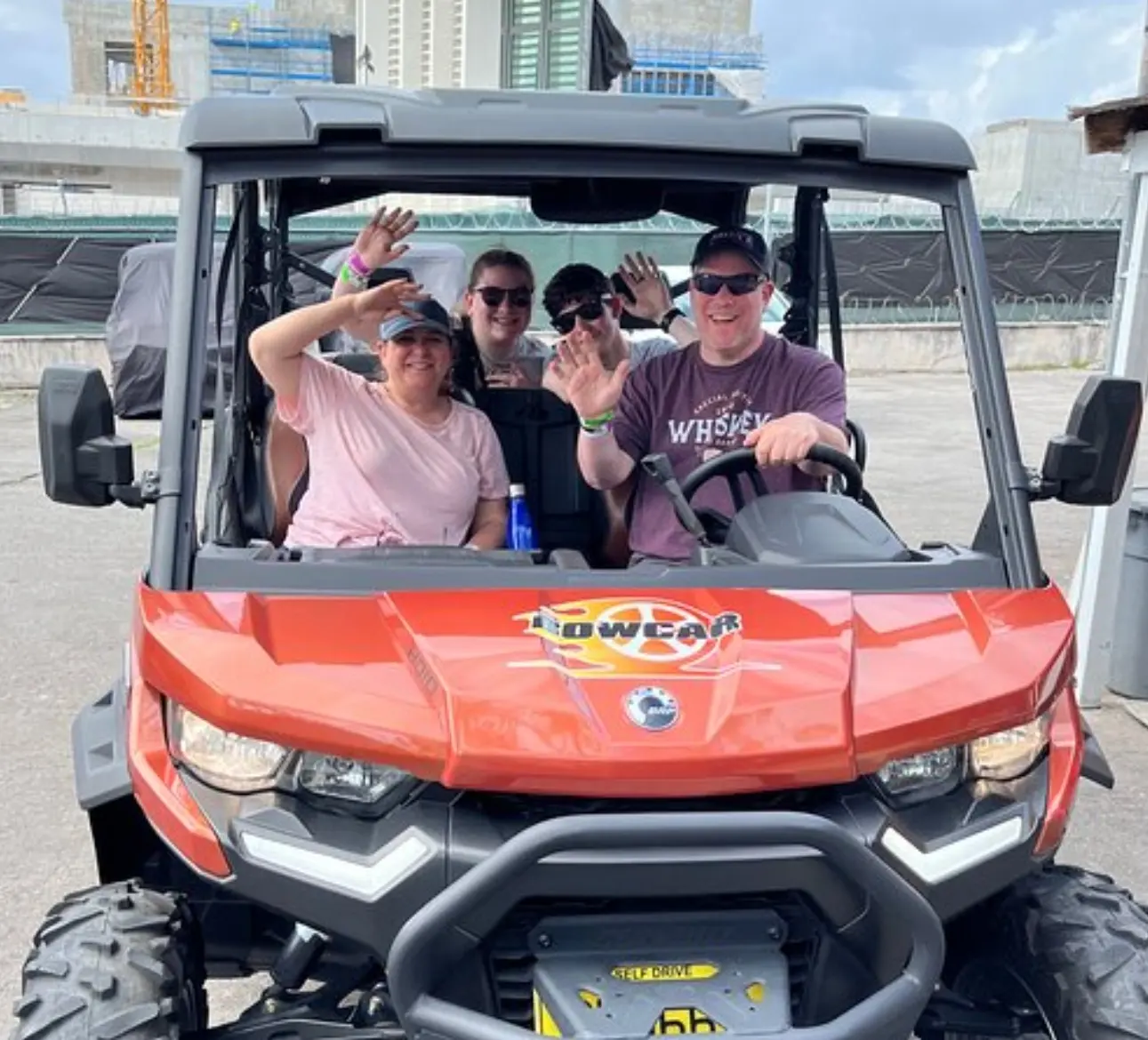Guests waving from an orange Bowcar jeep in Nassau