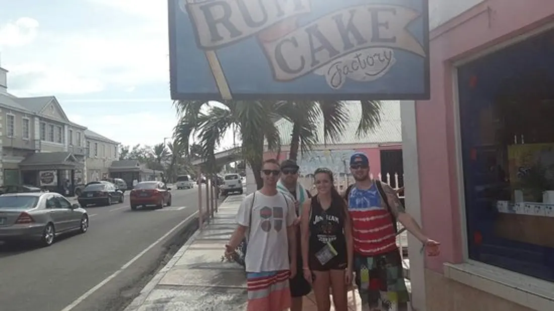 A group at the Bahamas Rum Cake Factory sign